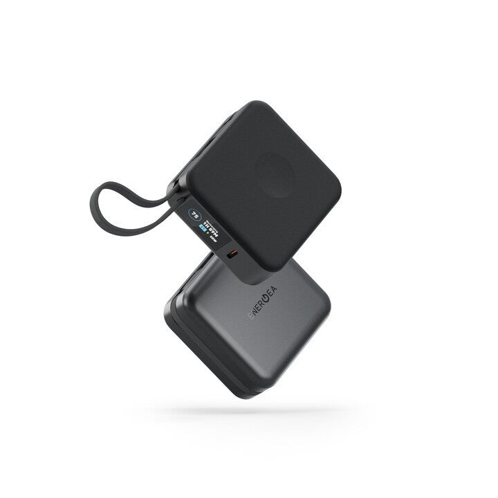 A pair of compact square power banks in matte black and dark gray, shown floating against a solid white background. One power bank is positioned above the other to display both the top and side views, including a wrist strap and a small digital battery percentage display.